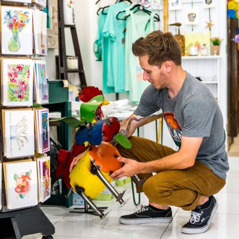 man looking at colorful metal dog lawn art at Simply Ashland gift store