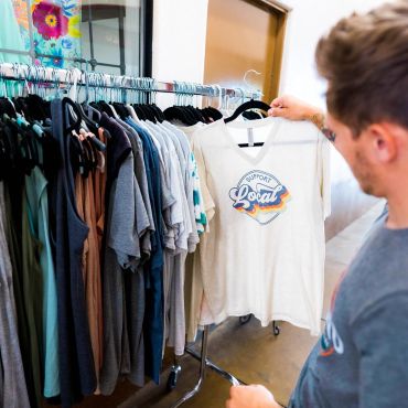 man holding colorful metal dog lawn art inside Simply Ashland gift shop