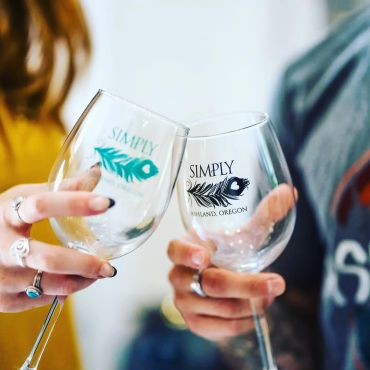 couple clinking Simply Ashland logo wine glasses